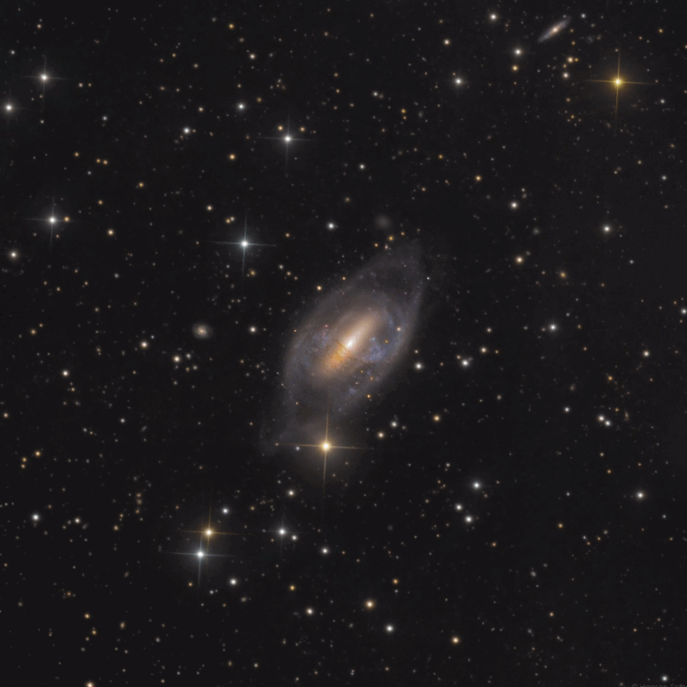 A spiral galaxy known as the Helix Galaxy (NGC 2685), showing its unusual ringed structure and tilted dust lanes, set against a backdrop of stars